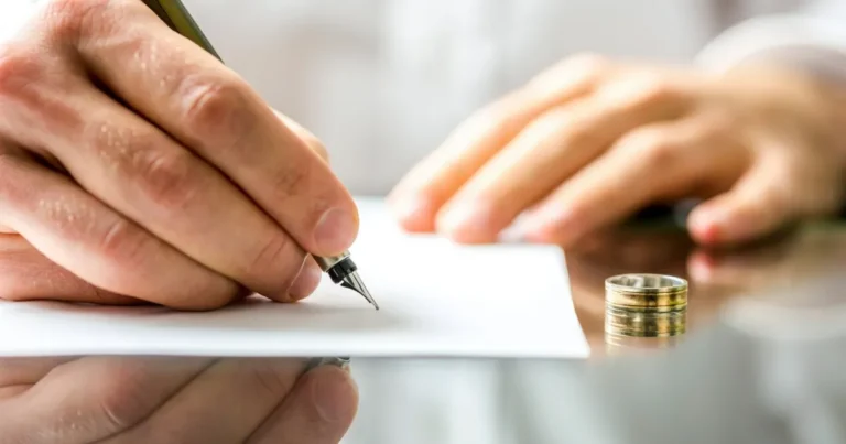 hands signing contested vs uncontested divorce with a ring sitting on the table